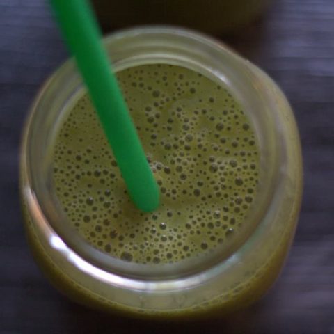 Green smoothie in glass with straw