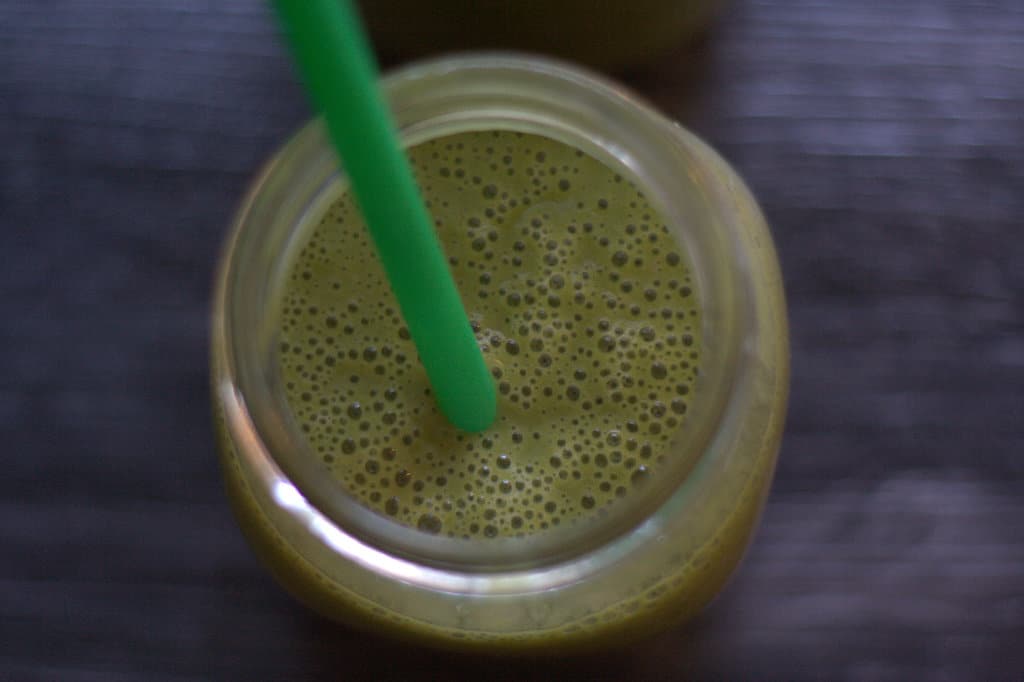 Green smoothie in glass with straw