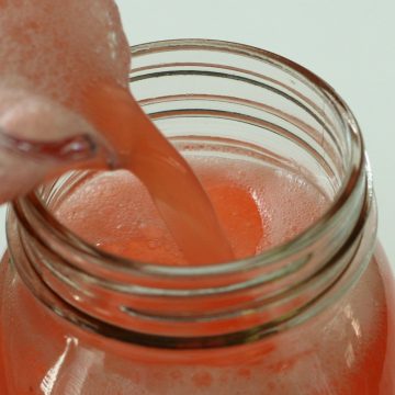 pink liquid being poured into mason jar