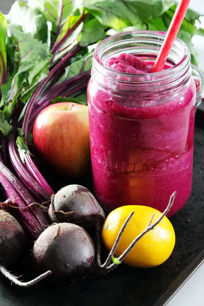 Smoothie in glass jar surrounded by fruits and vegetables