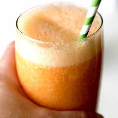 hand holding glass filled with orange liquid