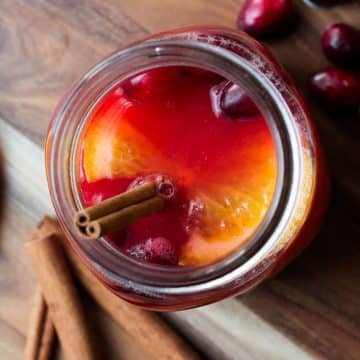 mulled cider served in mason jar topped with cranberries and a cinnamon stick