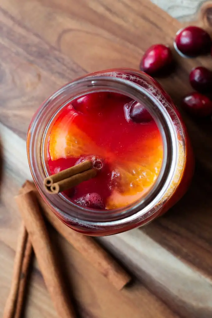 mulled cider served in mason jar topped with cranberries and a cinnamon stick