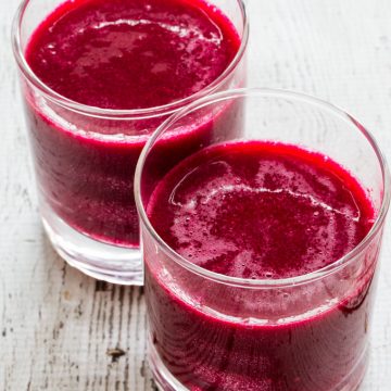 Two glasses filled with red beverage
