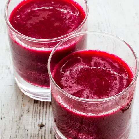 Two glasses filled with red beverage
