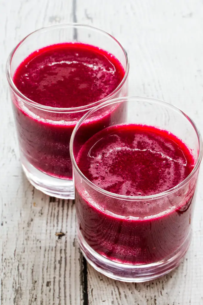 Two glasses filled with red beverage