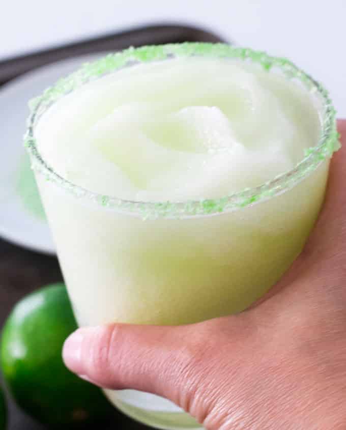 hand holding glass filled with lime margaritas