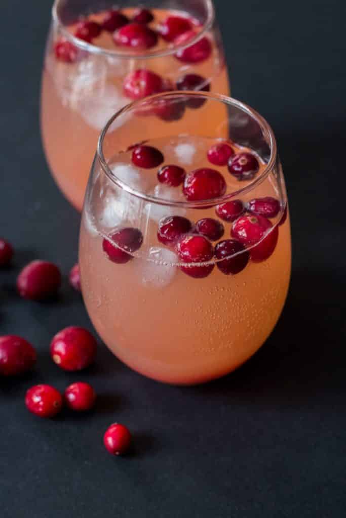 sparkling water being poured into glass with cranberries and ice